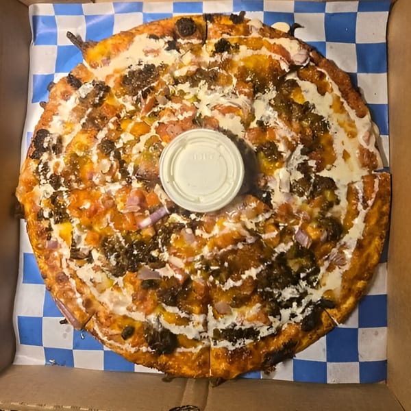 A Wild Duck Bar & Grill pizza with meat, onions, and white sauce, in a box.