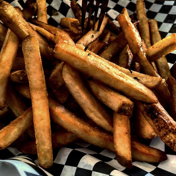 Close-up of golden-brown french fries in a black and white checkered paper basket at Wild Duck Bar & Grill.